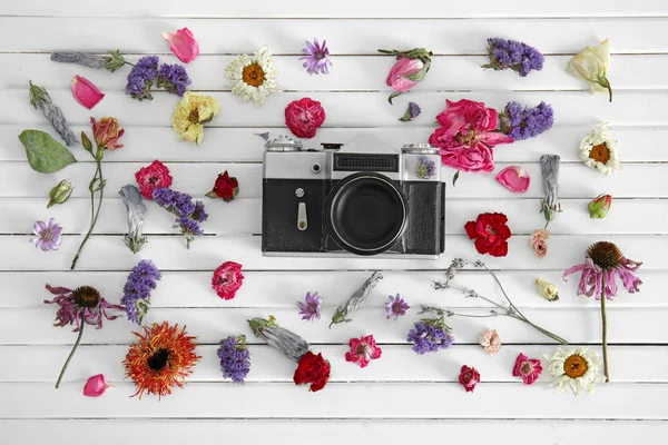 Beautiful composition of vintage camera and colourful flowers on white wooden background