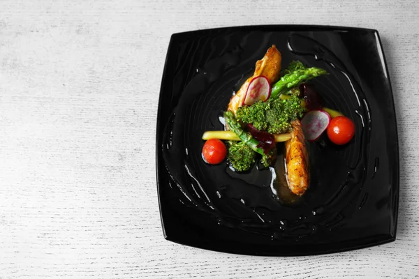 Fried chicken fillet with vegetables on black plate