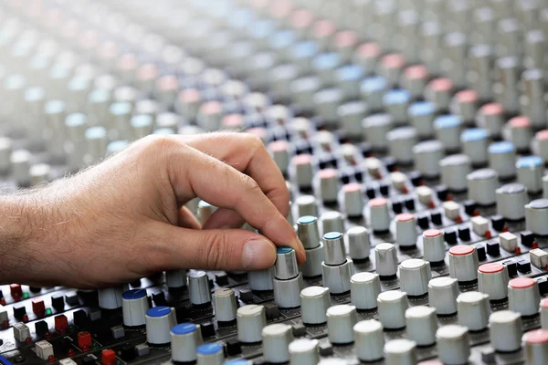 Hand on mixer in recording studio