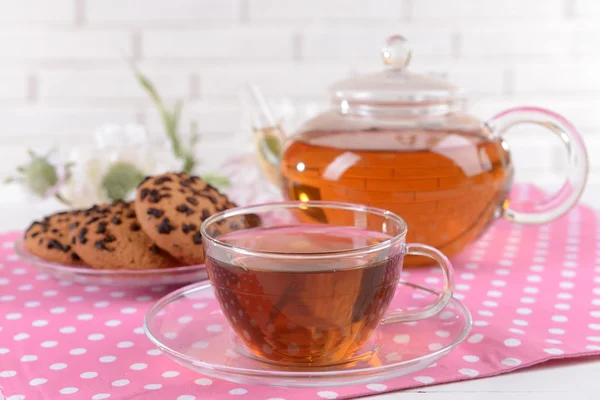 Teapot and cup of tea on table on brick wall background