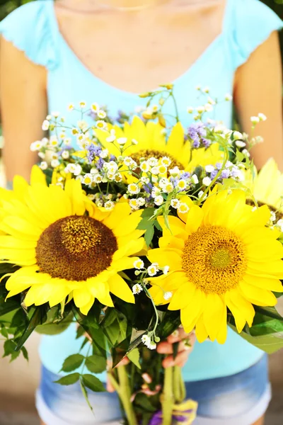 Beautiful bouquet of sunflowers in female hands