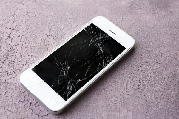 Modern mobile phone with broken screen on wooden background