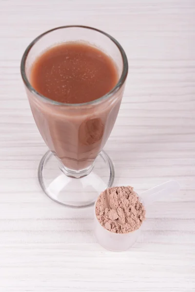 Whey protein powder and chocolate protein shake on wooden background