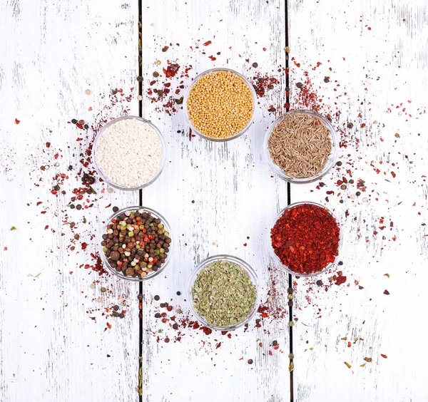 Spices in glass round bowls on wooden background