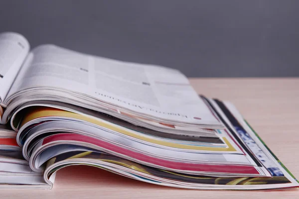 Magazines on wooden table on gray background