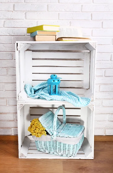 Wooden boxes with home things on white brick wall background