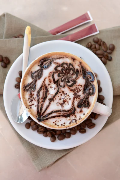 Cup of coffee with cute drawing on table, close up