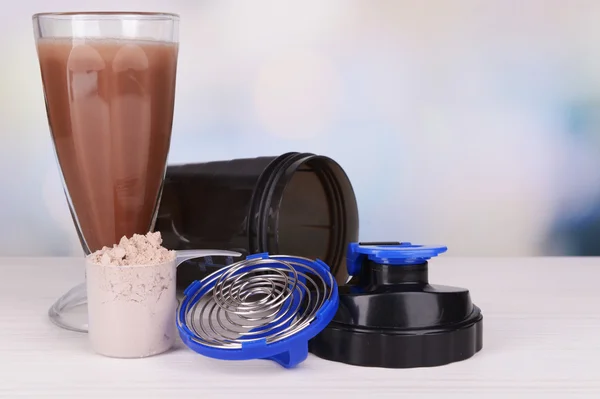Whey protein powder with shake and plastic shaker on table on bright background