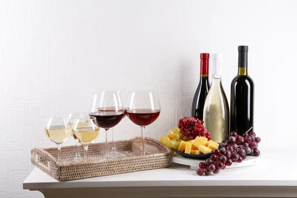 Bottles and glasses of wine and ripe grapes on table in room