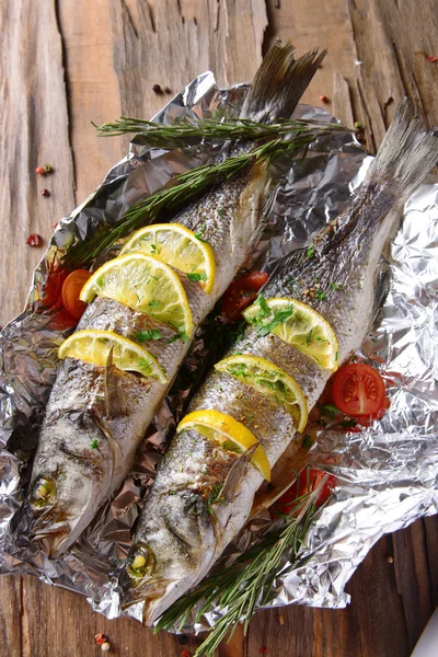 Tasty baked fish in foil on table close-up