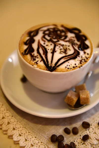 Cup of coffee with cute drawing on table, close up