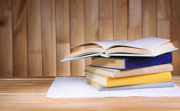 Books on wooden table on wooden wall background