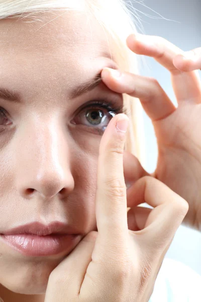 Medicine and vision concept - young woman with contact lens, close up