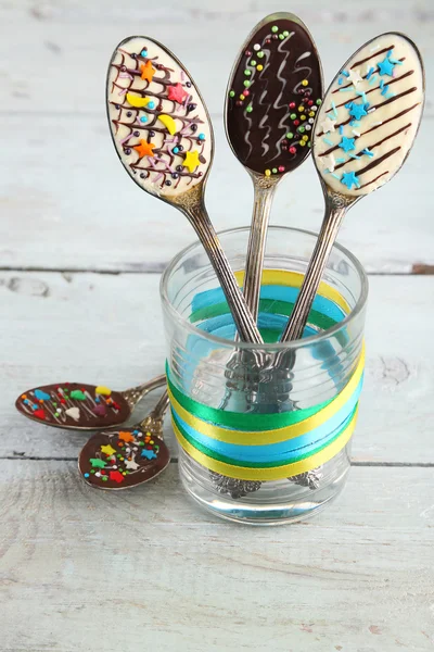 Spoons with tasty chocolate for party on old wooden table