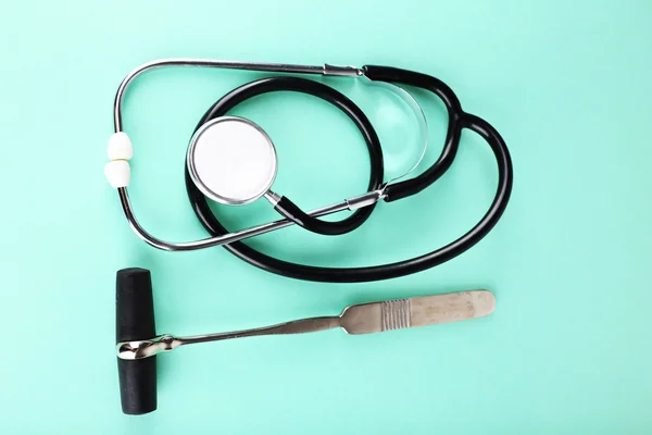 Stethoscope and reflex hummer on light background