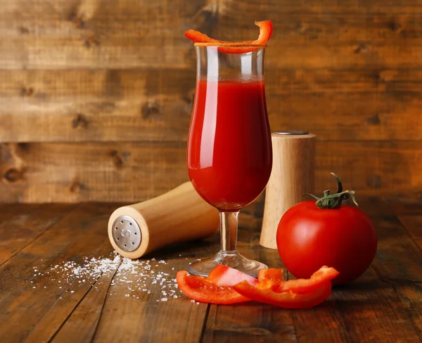 Glass of tasty tomato juice and pepper on wooden table