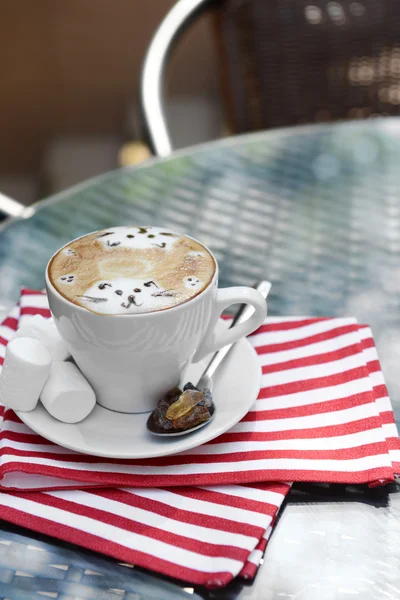 Cup of coffee with cute drawing on table, close up