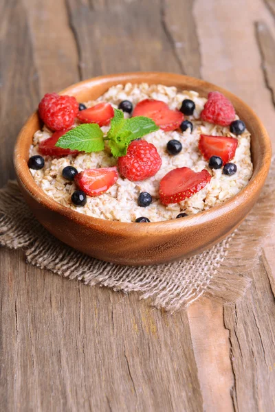 Tasty oatmeal with berries on table close-up