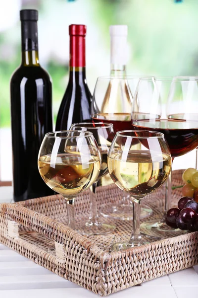 Bottles and glasses of wine and ripe grapes on table on natural background