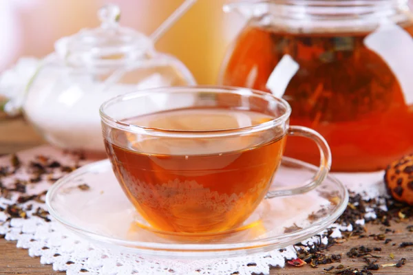 Teapot and cup of tea on table on light background