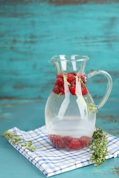 Tasty cool beverage with raspberries and thyme, on light background