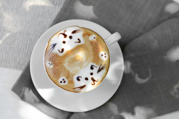 Cup of coffee with cute drawing on table, close up