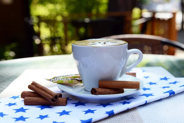 Cup of coffee with cute drawing on table, close up