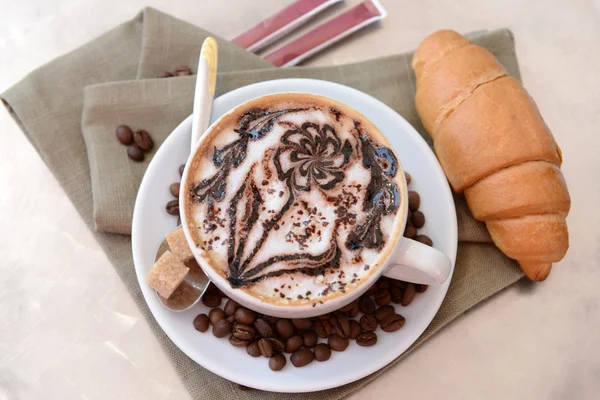 Cup of coffee with cute drawing on table, close up