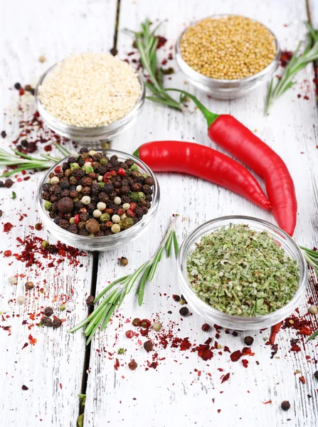 Spices in glass round bowls with herbs and chilly pepper on wooden background