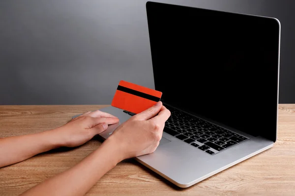 Hand holding credit card to buy online, on gray background