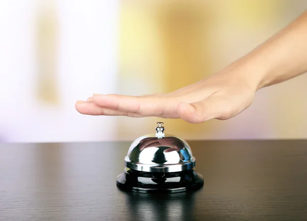 Female hand ring bell on  hotel reception desk