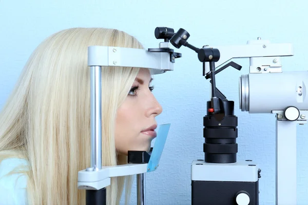 Optometry concept - pretty young woman having her eyes examined by eye doctor