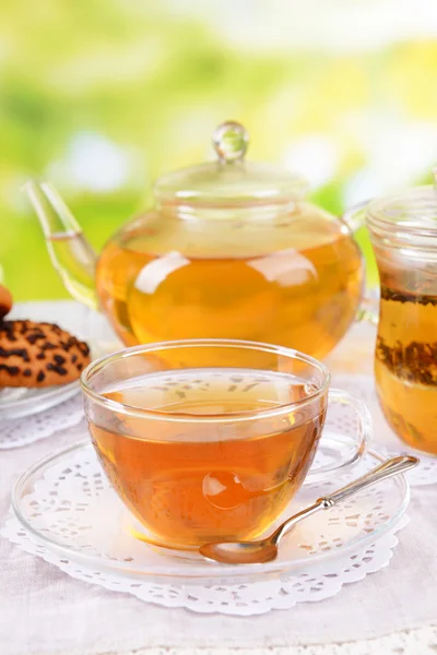 Teapot and cups of tea on table on bright background