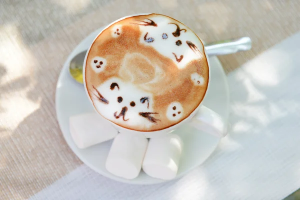 Cup of coffee with cute drawing on table, close up