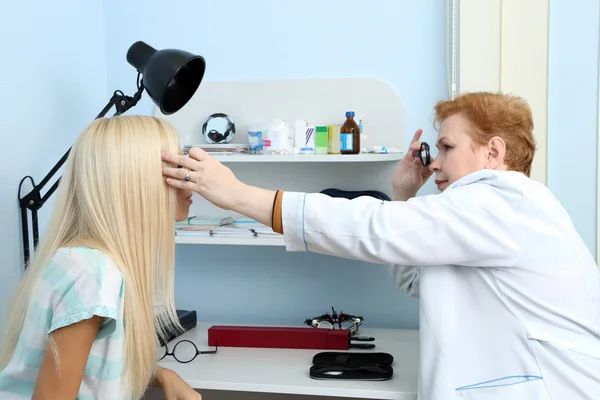 Optometry concept - pretty young woman having her eyes examined by eye doctor