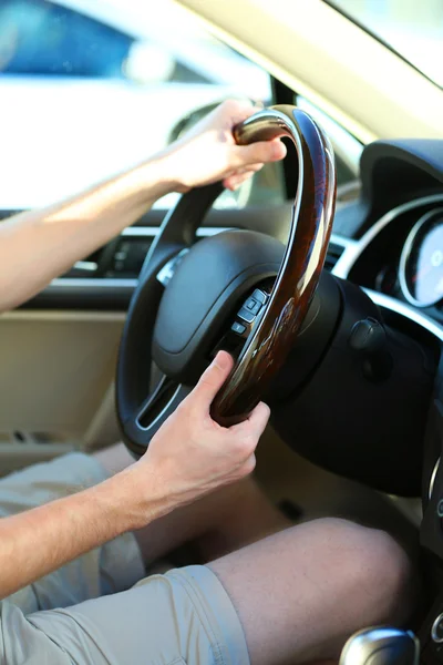 Man\'s hands on a steering wheel