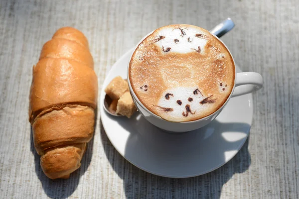 Cup of coffee with cute drawing on table, close up