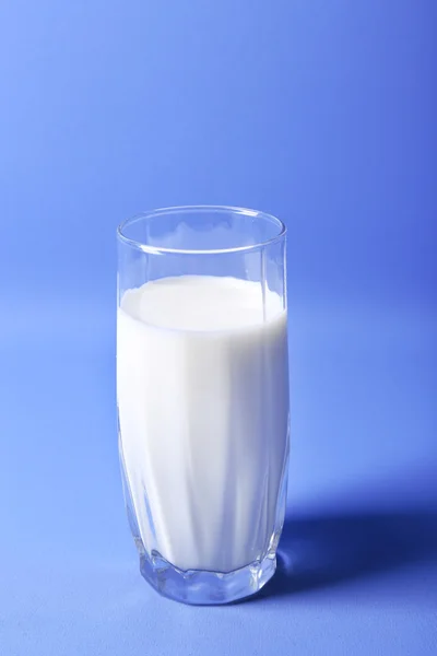 Milk in glass on blue background