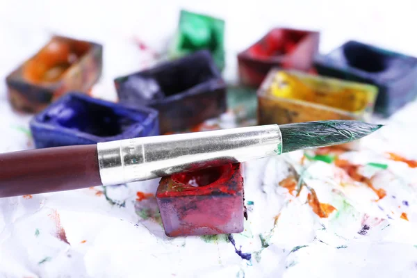 Watercolor paint cubes with brushes and spilled paint