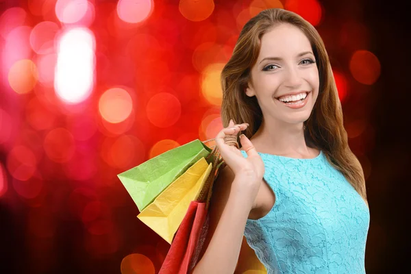 Shopping concept. Beautiful young woman with shopping bags on bright background