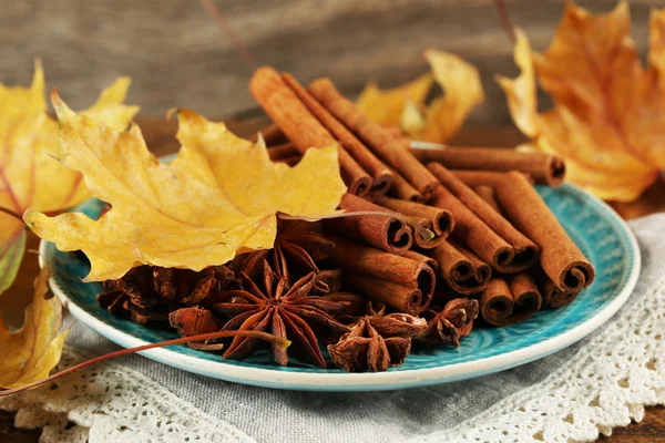Cinnamon sticks and stars anise with yellow leaves on wooden background