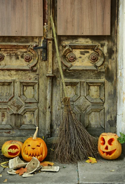 Pumpkin and broom for holiday Halloween on old wooden door background