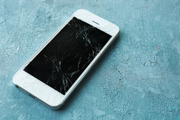 Modern mobile phone with broken screen on wooden background