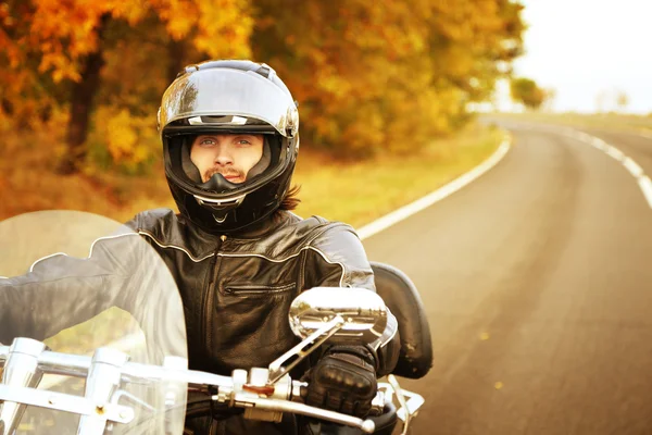 Biker man in black helmet sits on bike