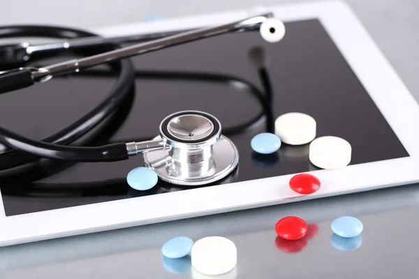 Stethoscope, pills, PC tablet on light background. medicine concept