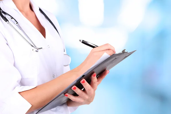 Young beautiful doctor holding folder on hospital background