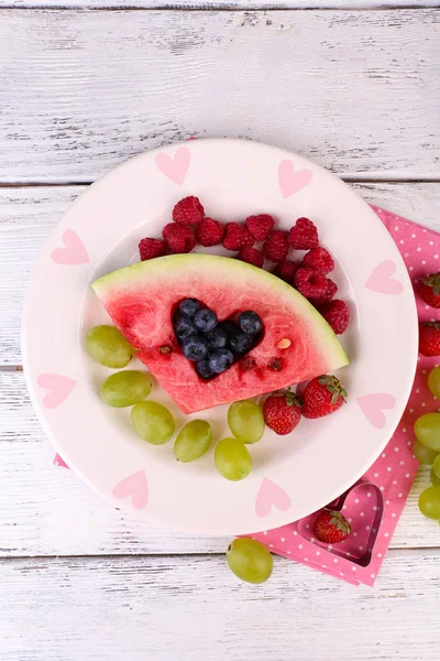 Fresh juicy watermelon slice  with cut out heart shape, filled fresh berries