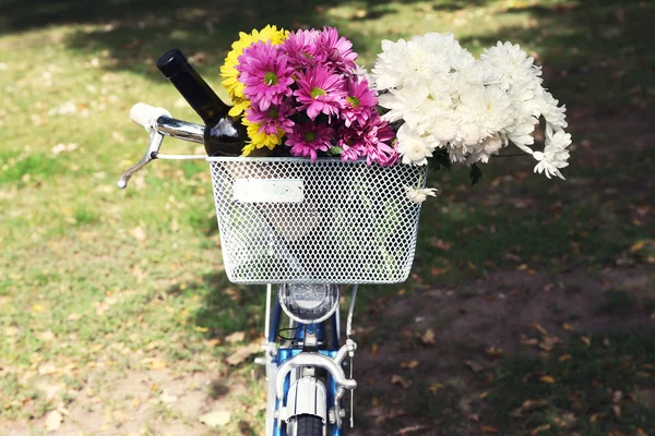 Bicycle with flowers and bottle of wine in metal basket closeup