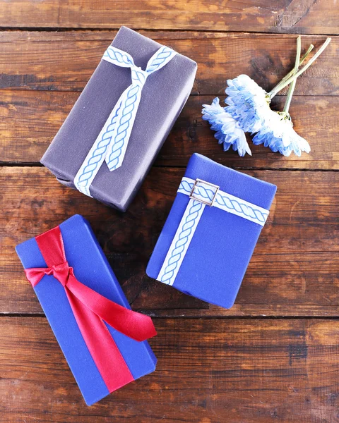 Three present boxes with flowers on wooden background