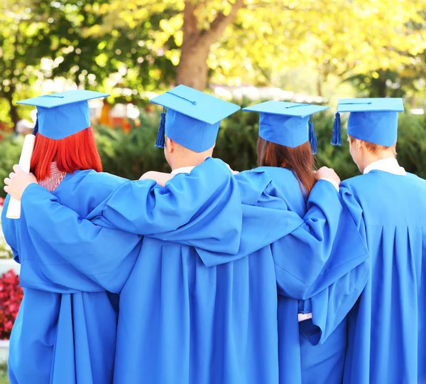 Graduate students wearing graduation hat and gown, outdoors